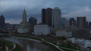 DX0001_002740 - 5.7K aerial stock footage reverse view of city skyline on the other side of the Scioto River at sunset, Downtown Columbus, Ohio