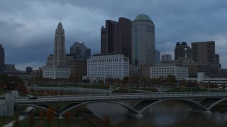 DX0001_002741 - 5.7K aerial stock footage ascend over bridge for view of city skyline by the Scioto River at sunset, Downtown Columbus, Ohio