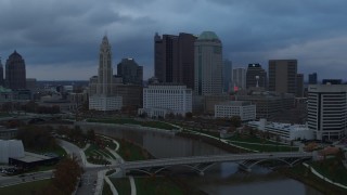 DX0001_002744 - 5.7K aerial stock footage descend with view of bridge and city skyline by the Scioto River at sunset, Downtown Columbus, Ohio