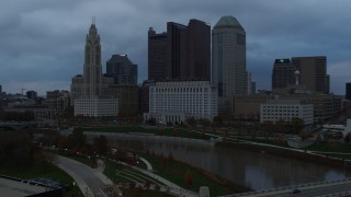 DX0001_002751 - 5.7K aerial stock footage flying by the city skyline and the Scioto River at sunset, descend to reveal bridge, Downtown Columbus, Ohio