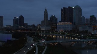 DX0001_002769 - 5.7K aerial stock footage flying by the river and the city skyline at twilight to reveal a bridge in Downtown Columbus, Ohio