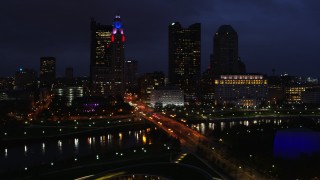 DX0001_002791 - 5.7K aerial stock footage of passing a bridge spanning the river and city skyline at twilight, Downtown Columbus, Ohio