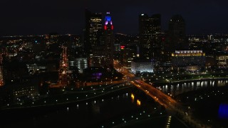 DX0001_002798 - 5.7K aerial stock footage of flying by the city skyline, and bridge spanning the river at night, Downtown Columbus, Ohio