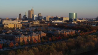 DX0001_002924 - 5.7K aerial stock footage of a view of the city's skyline at sunset, descend to reveal White River, Downtown Indianapolis, Indiana