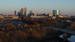 DX0001_002925 - 5.7K aerial stock footage of the city's skyline at sunset seen from White River, ascend over bridge, Downtown Indianapolis, Indiana