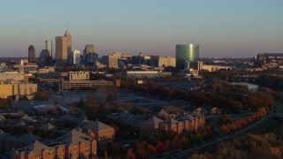 DX0001_002927 - 5.7K aerial stock footage of the city's skyline at sunset seen while ascending from White River, Downtown Indianapolis, Indiana