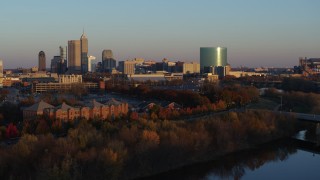 DX0001_002929 - 5.7K aerial stock footage of the city's skyline at sunset, seen during descent toward White River, Downtown Indianapolis, Indiana