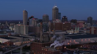 DX0001_002962 - 5.7K stock footage aerial video fly past smoke stacks at twilight with skyline in background, Downtown Indianapolis, Indiana