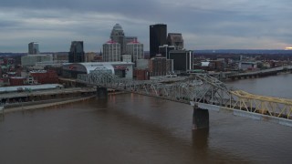 DX0001_003066 - 5.7K aerial stock footage of the arena and city skyline seen from a bridge spanning Ohio River at sunset, Downtown Louisville, Kentucky
