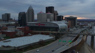 DX0001_003072 - 5.7K stock footage aerial video descend by freeway near the arena and city skyline at sunset, Downtown Louisville, Kentucky