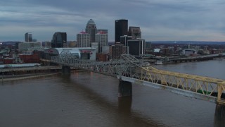 DX0001_003074 - 5.7K stock footage aerial video ascend by bridge spanning river at sunset for view of skyline, Downtown Louisville, Kentucky