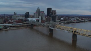 DX0001_003075 - 5.7K stock footage aerial video reverse view of bridge spanning river and city skyline at sunset, Downtown Louisville, Kentucky