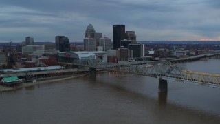 DX0001_003076 - 5.7K stock footage aerial video fly over the river to approach arena and city skyline at sunset, Downtown Louisville, Kentucky