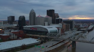 DX0001_003077 - 5.7K stock footage aerial video flyby river and bridge to pass arena and city skyline at sunset, Downtown Louisville, Kentucky