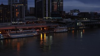 DX0001_003095 - 5.7K aerial stock footage orbit small riverboat beside a historic ship at twilight in Downtown Louisville, Kentucky