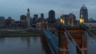 DX0001_003154 - 5.7K stock footage aerial video flyby the Roebling Bridge over the river at sunset, approach the skyline, Downtown Cincinnati, Ohio