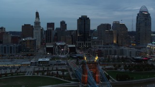 DX0001_003158 - 5.7K aerial stock footage ascend by Roebling Bridge for reverse view of Ferris wheel and city skyline at sunset, Downtown Cincinnati, Ohio