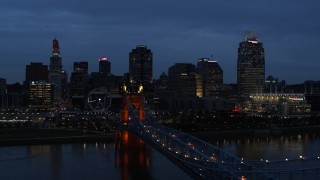 DX0001_003173 - 5.7K stock footage aerial video ascend from Roebling Bridge lit up at twilight, approach city skyline, Downtown Cincinnati, Ohio