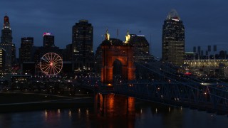 DX0001_003176 - 5.7K aerial stock footage approach end of Roebling Bridge and city skyline lit up at twilight, Downtown Cincinnati, Ohio