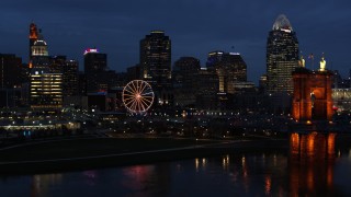 DX0001_003183 - 5.7K aerial stock footage fly away from skyscraper and Ferris wheel at twilight, reveal the river and bridge, Downtown Cincinnati, Ohio
