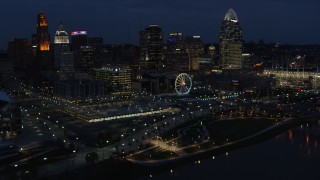 DX0001_003186 - 5.7K aerial stock footage reverse view of Ferris wheel and skyscrapers at twilight, reveal river, Downtown Cincinnati, Ohio