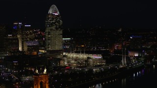 DX0001_003195 - 5.7K aerial stock footage of a tall skyscraper and the baseball stadium at night in Downtown Cincinnati, Ohio