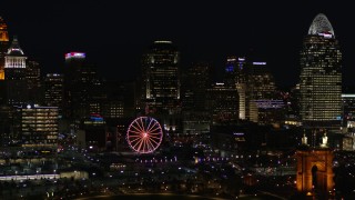 DX0001_003197 - 5.7K aerial stock footage ascend with a view of the city skyline and Ferris wheel at night, Downtown Cincinnati, Ohio