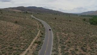 DX0001_007_027 - 5.7K stock footage aerial video of a black SUV cruising on a desert road in Carson City, Nevada