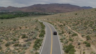 DX0001_007_032 - 5.7K stock footage aerial video of a black SUV driving by on a desert road in Carson City, Nevada