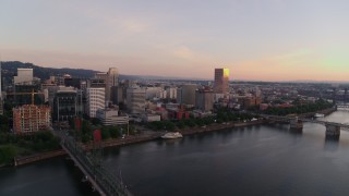 DX0001_010_009 - 4K aerial stock footage flying away from Morrison Bridge and over the Hawthorne Bridge at sunrise, Downtown Portland, Oregon