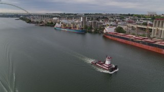DX0001_013_008 - 5.7K aerial stock footage tracking a tugboat sailing past cargo ships and North Portland, Oregon