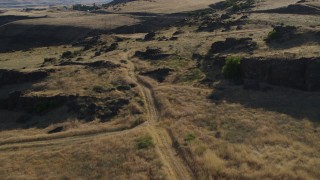 DX0001_019_030 - 5.7K aerial stock footage of ascending beside a dirt road to reveal Lewis and Clark Highway in Goldendale, Washington