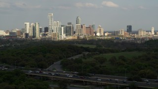 DX0002_104_022 - 5.7K aerial stock footage of a wide view of city's towering skyline, descend near freeway, Downtown Austin, Texas