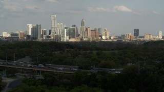 DX0002_104_023 - 5.7K aerial stock footage ascend from green trees by freeway for wide view of city's towering skyline, Downtown Austin, Texas