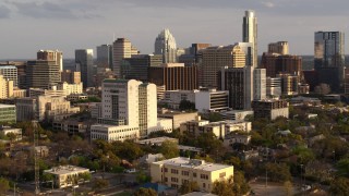 DX0002_104_039 - 5.7K aerial stock footage of flying by a courthouse and office buildings near skyscrapers at sunset in Downtown Austin, Texas