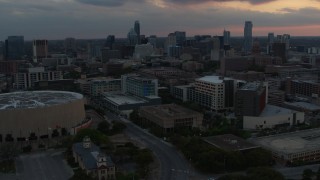 DX0002_105_017 - 5.7K aerial stock footage approach hospital with skyscrapers in the background at sunset in Downtown Austin, Texas