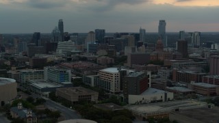 DX0002_105_024 - 5.7K aerial stock footage approach hospital, skyscrapers and capitol dome in distance at sunset in Downtown Austin, Texas