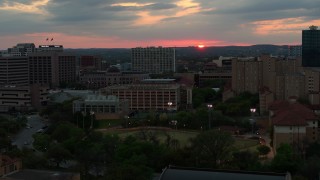 DX0002_105_028 - 5.7K aerial stock footage of the distant setting sun while flying past the university, Austin, Texas