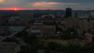DX0002_105_031 - 5.7K aerial stock footage of ascending by the university campus with setting sun in distance, Austin, Texas