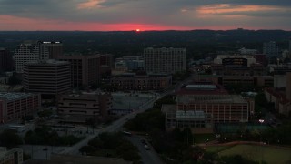 DX0002_105_034 - 5.7K aerial stock footage stationary view of setting sun before flying by university campus, Austin, Texas
