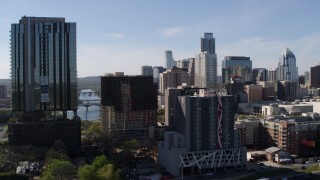 DX0002_108_046 - 5.7K aerial stock footage of flying by a high-rise with a view of the city's skyline in Downtown Austin, Texas
