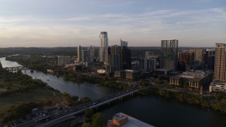 DX0002_110_003 - 5.7K aerial stock footage reverse view of the city's waterfront skyline and Lady Bird Lake at sunset in Downtown Austin, Texas