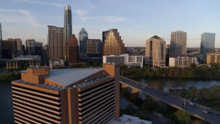 DX0002_110_007 - 5.7K aerial stock footage fly away from waterfront skyscrapers across Lady Bird Lake at sunset, reveal hotel in Downtown Austin, Texas