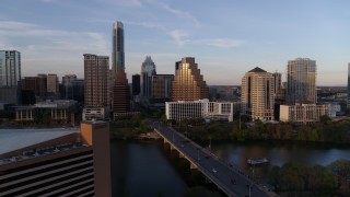 DX0002_110_015 - 5.7K aerial stock footage fly away from skyline, and bridge over Lady Bird Lake at sunset in Downtown Austin, Texas