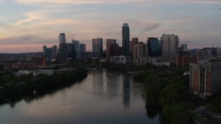 DX0002_110_021 - 5.7K aerial stock footage slowly fly over Lady Bird Lake toward the city's skyline at sunset in Downtown Austin, Texas