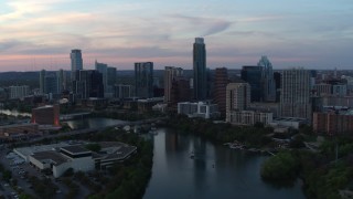 DX0002_110_024 - 5.7K aerial stock footage slowly fly away from city skyline by Lady Bird Lake at twilight in Downtown Austin, Texas