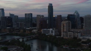 DX0002_110_029 - 5.7K aerial stock footage reverse view of The Austonian and city skyline beside Lady Bird Lake at twilight in Downtown Austin, Texas