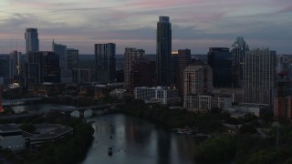 DX0002_110_030 - 5.7K aerial stock footage of The Austonian towering over city skyline beside Lady Bird Lake at twilight in Downtown Austin, Texas