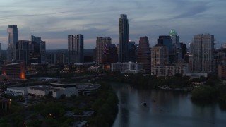 DX0002_110_033 - 5.7K aerial stock footage of The Austonian and city skyline seen while passing over Lady Bird Lake at twilight in Downtown Austin, Texas