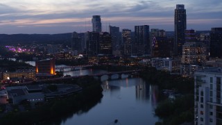 DX0002_110_044 - 5.7K stock footage aerial video reverse view of Congress Avenue Bridge, Lady Bird Lake, skyline at twilight in Downtown Austin, Texas